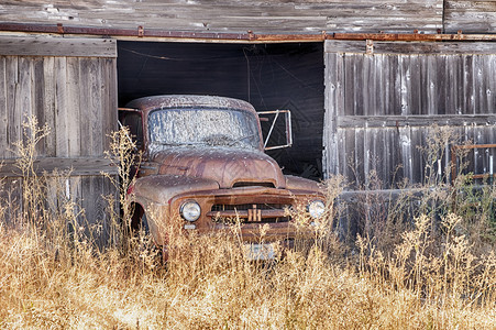 农场一辆旧红色卡车停在农村的谷仓里车上停放着一辆红色老卡车上有挡风玻璃面盖满了鸟粪层木头哈特莱恩图片