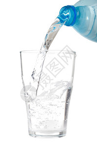 新鲜的浇注将塑料瓶倒在白底隔绝的玻璃杯上闪发光的图片