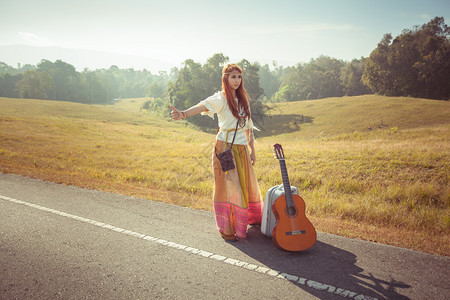 冒险复古的带吉他搭便车的嬉皮女孩在农村公路上门户14图片
