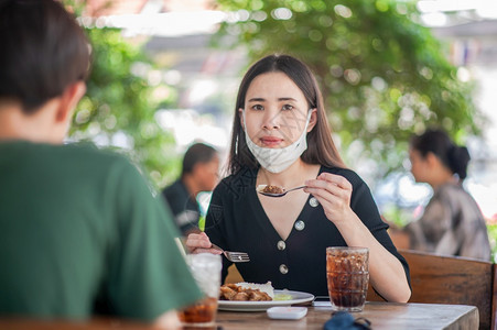 亚洲女孩顾客裔使用面罩坐在餐厅软焦点新正常概念的餐饮中图片