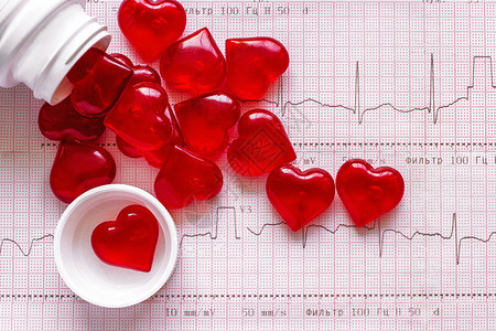 以红心形式在脑ECG卡片背景上标出的数字瓶状和散落的红心形数字健康脏维他命概念罐为了药丸图片