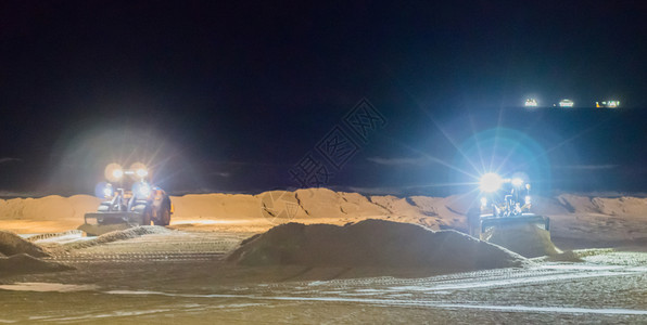 地面工人夜间在沙滩上用推土机工作图片