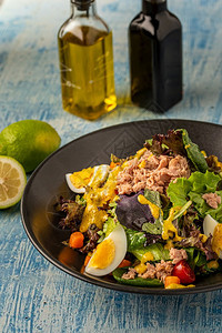 晚餐可口蔬菜黑盘上含蛋和金鱼的新鲜地中海沙拉图片
