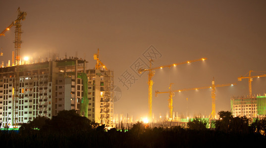 工业建造起重机和夜间建筑的设水泥摩天大楼屋图片