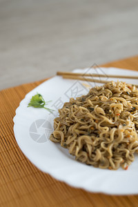 日本人意大利面餐桌上有竹棍的面条和牛肉在矩形盘中亚洲人图片