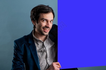 介绍信息快乐的男人拿着蓝色海报快乐微笑的年轻人展示空白招牌与的复制间区域用于标语或广告短信概念中的白种人男模常设图片