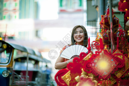 肖像更年轻人身着传统服装的妇女在白兰地的Yaowarat街Chipa镇面带笑脸的竹子风扇牙图片