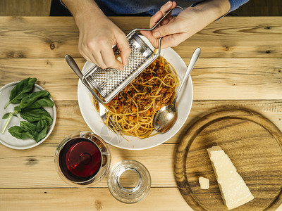 超过午餐起司一位女用杯红葡萄酒在碗传统意大利面汤上盛着干酪奶的女士照片图片