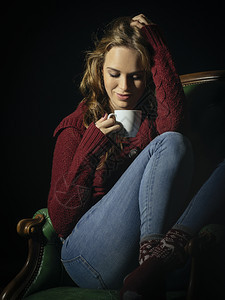 老的一位美丽年轻女子坐在旧皮椅上喝咖啡的照片她当时正坐在一张旧的皮椅上快乐女图片