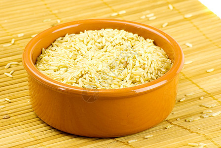 在竹垫上的陶瓷碗中有机棕色长稻烹饪超过谷物图片