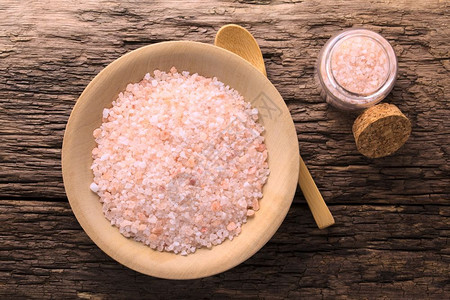 木板勺和小杯盐瓶上方的椰子粉红喜马拉雅盐拍摄了相片CorarPink喜马拉雅盐矿物岩石粉红色图片