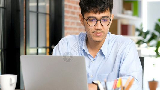 信息亚洲办公室人专注于在办公室使用笔记本电脑年轻商人在笔记本电脑上沉思亚洲男商人和办公室生活方式概念技术专业的图片