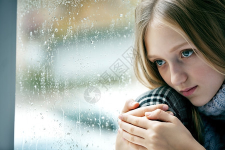 沮丧秋天女孩们一个长金发头的悲伤女孩情感肖像她坐在雨秋日的窗口上图片