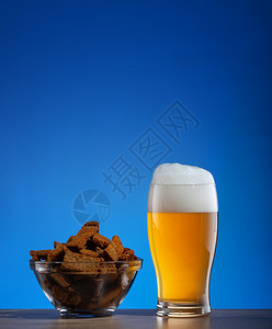 液体酒吧酥脆一杯淡啤酒和黑麦饼干放在蓝色背景的透明盘子里一杯啤酒和黑麦饼干放在蓝色背景的盘子里背景