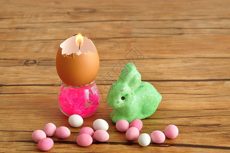 白色的种类一个空蛋壳变成一根蜡烛装在个小容器里上面放着一只绿兔子和粉红白糖果供复活节者使用传统图片