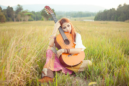 美丽的乡村嬉皮女孩在草地上弹吉他漂亮的肖像图片