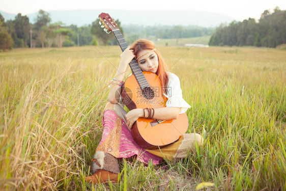 美丽的乡村嬉皮女孩在草地上弹吉他漂亮的肖像图片