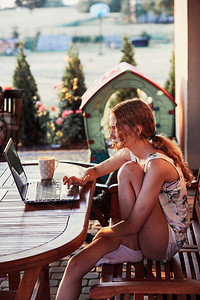 妇女在家里工作使用便携式计算机在夏季日坐院子上工作享受人真实时刻和情况随意的教育在职图片