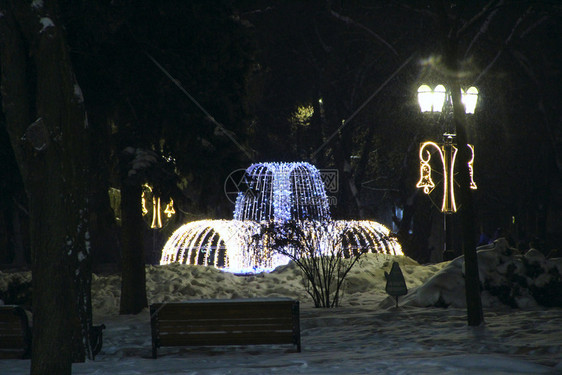 建筑的派对新年圣诞灯明夜街绿笼在城市公园亮灯照黑暗的花园光灯泉喷黑夜的花圈岗香朵开亮灯和喷泉路图片