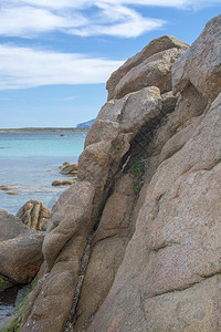 结石蓝色的在意大利撒丁亚州萨尔斯梅拉达岛海滩上的绿色水和花岗岩巨石在斯梅拉尔达萨丁尼亚岛海滩上的垂直图像绿色水和花岗岩巨石一种图片