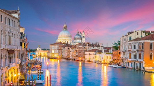 在意大利威尼斯的运河圣玛丽亚德拉萨卢特巴西利卡在黄昏时的背景中游客旅日落图片