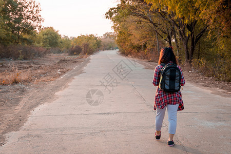 徒步旅行者搭便车健康带背在沥青路农村地区行走的女旅妇图片