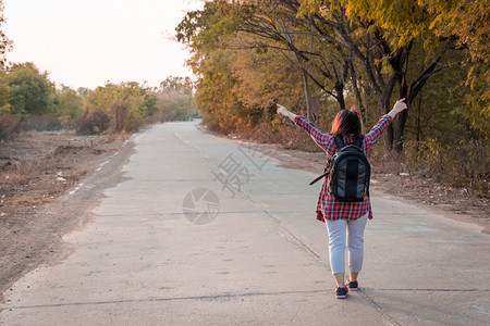 徒步旅行漂亮的肖像带背在沥青路农村地区行走的女旅妇高清图片