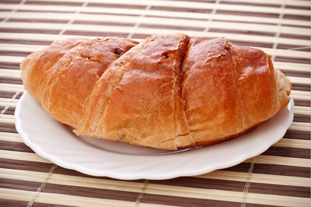 碟子白盘上铺着单一新鲜羊角面包早餐法语图片