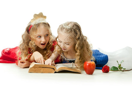 红色的服装朋友两个美丽的小女孩穿着长金发著红苹果和玫瑰的魔法书公主装饰着红色苹果和玫瑰图片