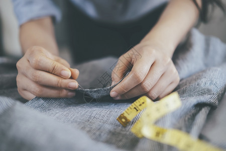 衣服工作室在桌上缝纫的年轻女裁穿着工作桌上的锯皮夹克针线活图片