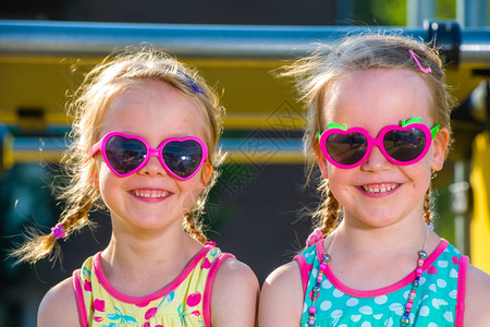 可爱的姐妹们双欢笑的胞胎仰望着摄影机童年微笑图片