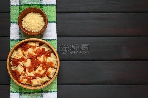 地中海食物用木碗里自制番茄酱和小碗里芝士加奶酪用自然光照在黑木头的上方照片拍图片