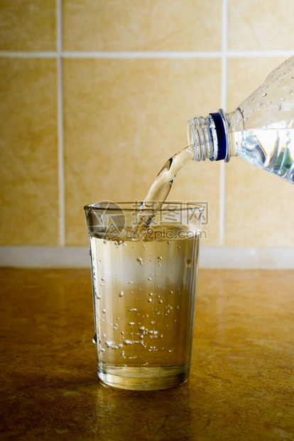 饮料瓜拉纳皮瓶子从塑料中将新鲜矿泉水倒入厨房的一个简单玻璃杯里图片