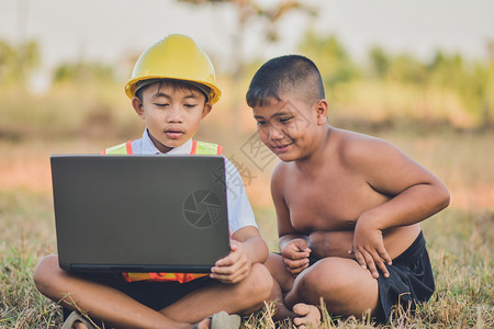 笔记本电脑乐趣教育男孩子在户外使用计算机制造硬帽图片