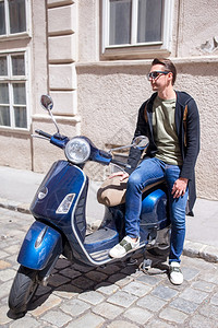 参观充满活力欧洲老城郊外骑摩托车的年轻人男子背景前欧洲老城以自拍为背景的年轻人图片