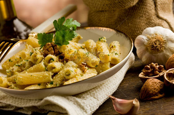制作意大利地区盘子由意大利面条和木制桌上的胡桃虫粉制成酱奶油的图片