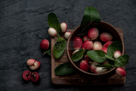 新鲜的生卡隆达孟加拉醋栗Carandas李子或Karonda水果CarissacarandasL酸味水果在柳条木杯中从顶部斜视图图片