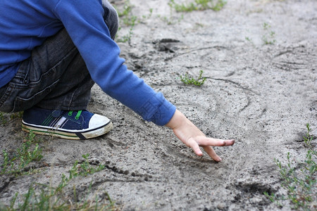积极的活动儿童坐下来在不同形状的沙中抽一根手指头并用向不同形状的沙子土壤背景图片