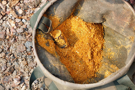 太阳金属饲料加满了在帆布桶里捕鱼的红色诱饵在油布桶中捕鱼的红色诱饵装在拖拉布桶内捕鱼的红诱饵一种自然图片