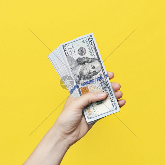 或者账单投资手持一大堆在黄背景上与世隔绝的钞票财富或贷款概念手持有一堆在黄背景上与世隔绝的钞票图片
