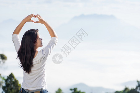 手势制造亚洲女双手以心形式与山地和天空对立手以爱的心形状手以爱的心形状假期图片