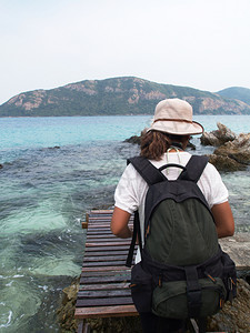 经过自然海边的木桥上行走旅游者后面是大海和山峰女图片