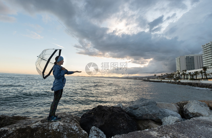 自由女孩在沙滩上与雨伞在阴云的一天女海滩图片