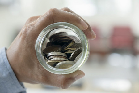 生长经济商人节约钱的概念手拿硬币装在玻璃瓶里利润图片