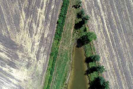 抽象的飞行天线从空中对一个渔池的角端进行摘要浏览该池在收获农田旁有一排树木图片