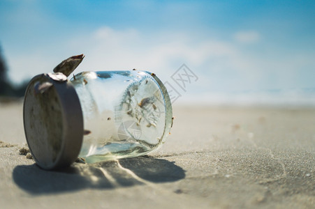 沙滩上的阳光海浪和玻璃瓶图片