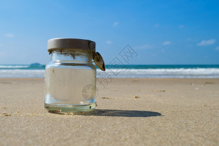 沙滩上的阳光海浪和玻璃瓶图片