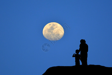 轮廓母亲和儿子在山上看月蓝背景时站在山上看着月亮蓝色背景距离家庭图片