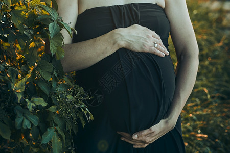 怀孕妇女拥抱肚子站在户外被大自然包围着的外表怀孕期待母概念中段出生希望图片