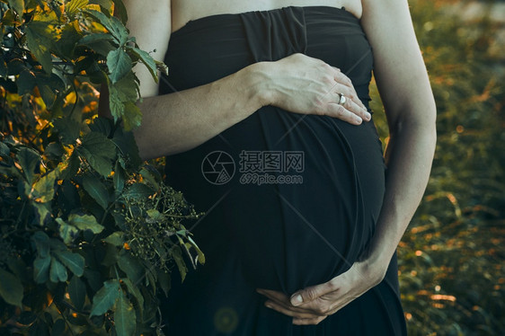 怀孕妇女拥抱肚子站在户外被大自然包围着的外表怀孕期待母概念中段出生希望图片